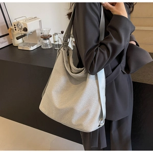 Silver glitter tote bag with gray nylon strap shown in a stylish cafe setting