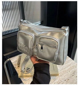 Close-up of silver metallic PU crossbody bag with dual front zipper pockets and logo