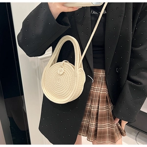 Detailed macro of beige hand-woven round cotton bag featuring an engraved wooden button