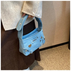 Détail d'un sac à main en jean bleu clair avec clous en métal étoile et cœur et bords effilés