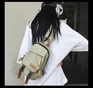 Detail of light green nylon crossbody bag showing the branded patch and strap on a person