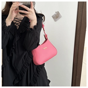 Detail of a bright pink underarm bag with gold hardware and an adjustable shoulder strap