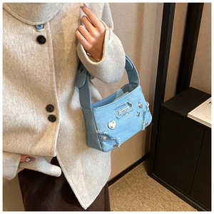Détail du sac à main en jean bleu clair avec clous en métal et bords effilochés