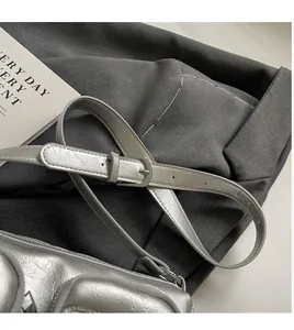 Detail of adjustable silver metallic shoulder strap with buckle on a Y2K crossbody bag
