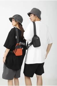 Outdoor style nylon crossbody bags in black and orange shown on models in a studio