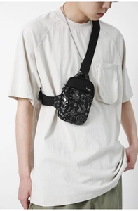 Détail du sac de poitrine en nylon noir avec imprimé graffiti de monstre blanc
