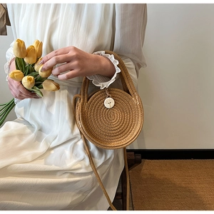 Detail of hand-woven round straw bag with natural texture and elegant wood buckle closure