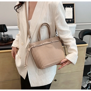Detail of beige pleated faux leather crossbody bag with drawstring and top handle