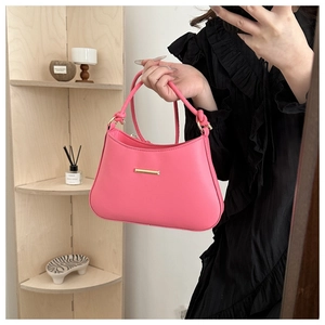 Close-up of rose pink underarm bag with gold metal buckle held against black dress