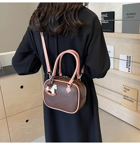 Brown and pink PU leather crossbody bag with wooden horse charm shown on a model