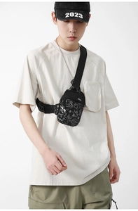 Détail du sac de poitrine en nylon noir avec motif graffiti blanc et bandoulière réglable