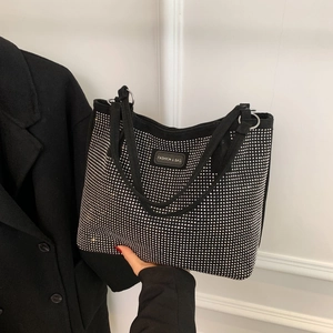 Detail of a black rhinestone tote bag showing sparkling crystals and fashion branding
