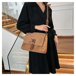 Close-up of brown faux suede messenger bag with leather strap worn by a model
