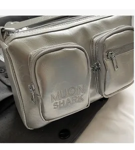 Close-up of silver PU crossbody bag featuring wrinkled texture and MUON SHARK branding