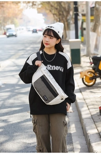Vue urbaine d'un grand sac de poitrine en nylon blanc porté avec une tenue streetwear