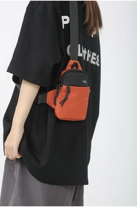 Detailed close-up of orange and black oxford fabric crossbody bag with zipper detail