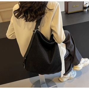Detail of a black glitter hobo bag with adjustable nylon strap shown on a model