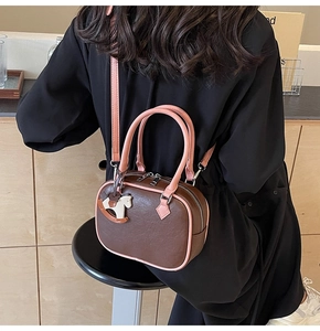 Detail showing the brown PU leather bag with pink straps and a white horse charm on a model