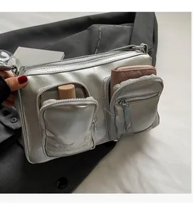 Detail view of silver metallic PU crossbody bag showing multiple functional zipper pockets
