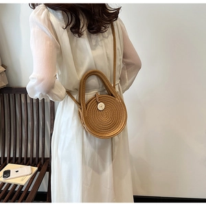 Detail view of round straw woven handbag with sunflower button and crossbody strap
