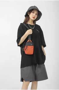 Trend sporty crossbody bag in orange and black worn by model in minimalist studio