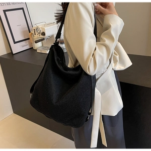 Detail of black glitter hobo bag with adjustable strap shown on model in blazer