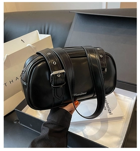 Close-up of black PU leather pillow bag with silver metal buckles and logo detailing
