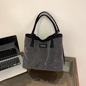 Fashionable black tote bag with silver rhinestones and dual handles on a desktop