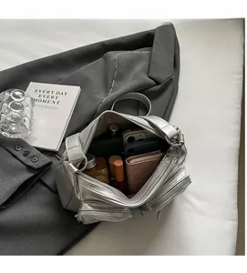 Top view showing spacious interior of silver metallic handbag with daily essentials inside