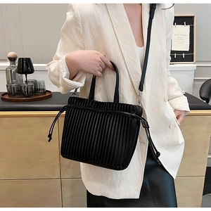 Close-up of black pleated PU leather crossbody bag with drawstring detail and slim strap