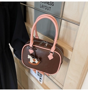 Detail view of contrast PU leather handbag with pink handles and rocking horse charm