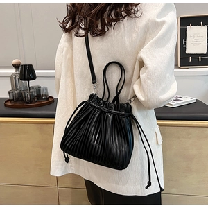 Close-up of stylish black pleated PU leather bucket bag with drawstring and ring handles