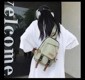 Detail of light green nylon crossbody bag with black buckle and durable brown strap