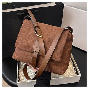 Brown suede crossbody bag with adjustable leather strap and golden hardware in a gift box