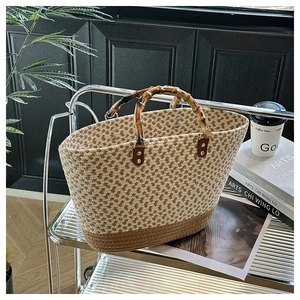 Woven tote bag with bamboo handles and contrast stitching displayed on a shelf