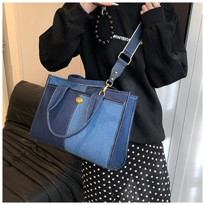 Detailed view of color-block denim crossbody bag with metal lock and blue woven strap