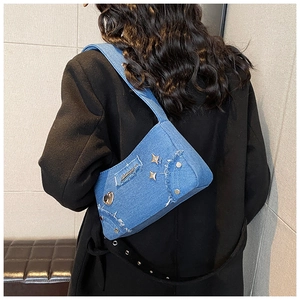 Gros plan du sac bandoulière en denim bleu avec bords effilochés et rivets étoiles