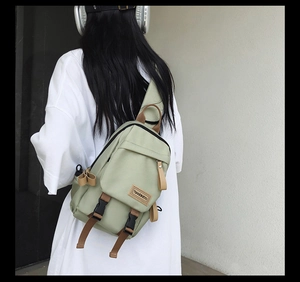 Detail of light green nylon crossbody bag with brown woven strap and brand leather patch