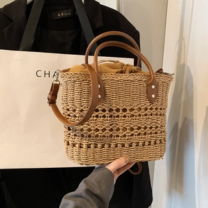 Chic beige straw woven handbag with brown leather handles and adjustable shoulder strap