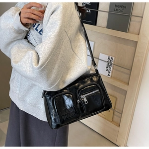 Close-up of black PU leather crossbody bag featuring dual front pockets and metallic zippers