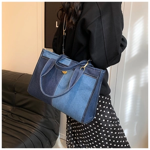 Detail view of large denim patchwork tote bag with stylish gold metal hardware