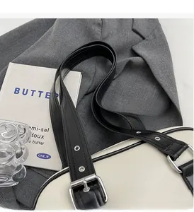 Close-up of adjustable wide shoulder strap with silver eyelets on a bicolor PU leather bag