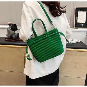 Detail of green pleated PU leather handbag featuring vertical folds and crossbody strap
