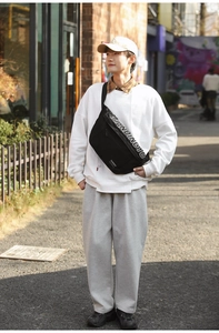 Détail de la sangle réglable et du logo blanc sur un sac banane noir en nylon résistant