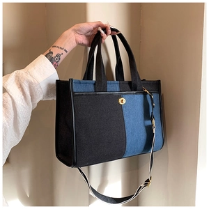 Detail of blue denim and black canvas tote bag with woven strap and golden buckle