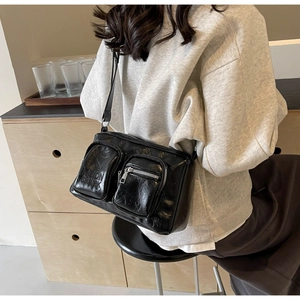 Detail of black glossy PU leather crossbody bag with dual pockets and adjustable strap