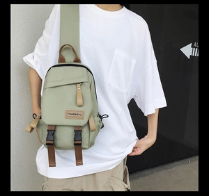 Detail of pea green nylon crossbody bag showing the adjustable strap and brand logo patch