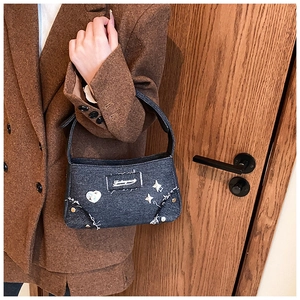 Détail du sac bandoulière en denim gris foncé avec broderie coeur et rivets