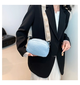 Close-up of light blue PU leather crossbody bag with rose embossed texture and strap