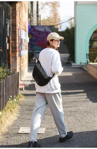 Détail du sac banane en nylon noir avec texte blanc et large bandoulière ajustable